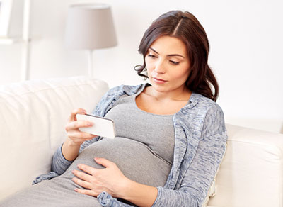 Hispanic pregnant woman looking at her phone for pregnancy help